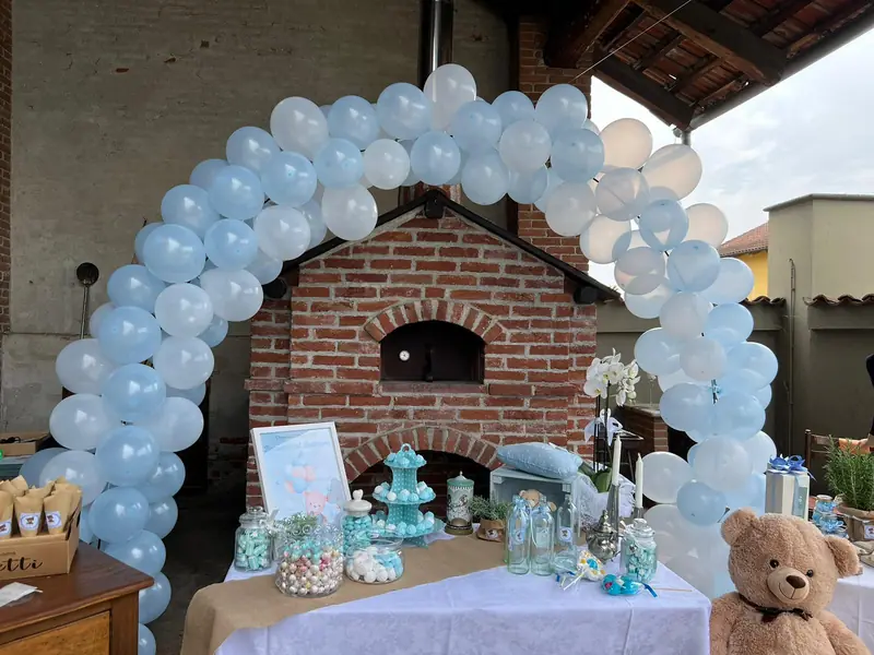 Arco di palloncini e tavolo dei confetti davanti al forno a legna