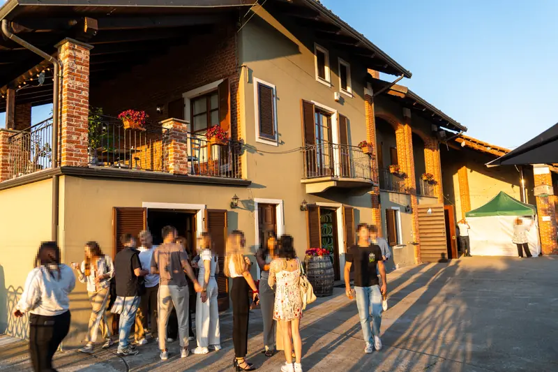 Facciata della cascina con gli ospiti nel cortile al tramonto